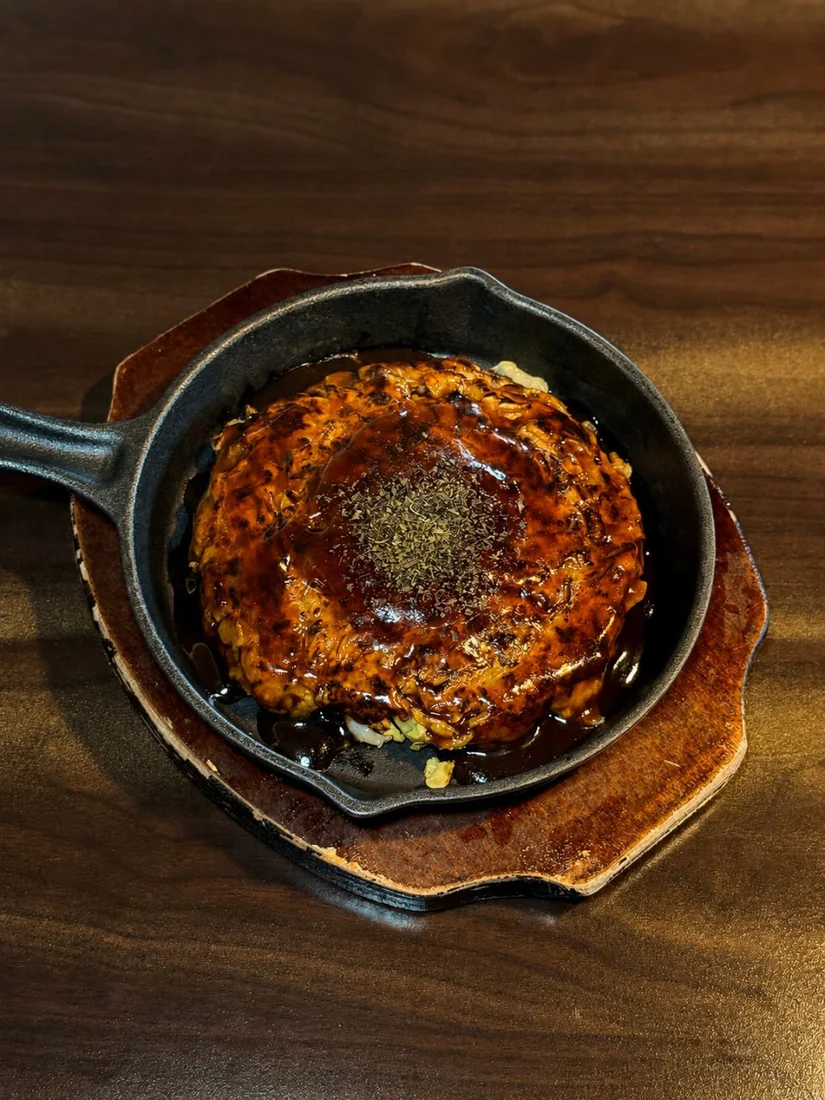 木の台に載せた鉄鍋のGooSaお好み焼き